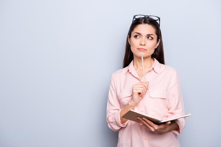 Thoughtful woman holding notebook and pen, representing the importance of choosing effective study methods over prep questions.