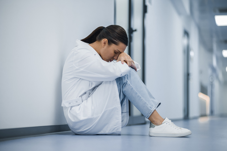 Stressed doctor sitting in hallway, symbolizing support and study schedules for pediatricians who failed board exams to succeed.