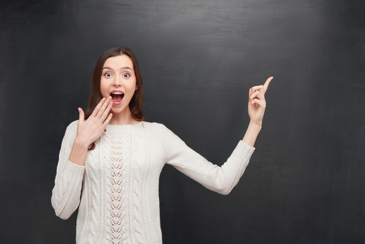 Excited woman pointing at chalkboard, representing effective test-taking strategies for success on pediatric medical board exams.