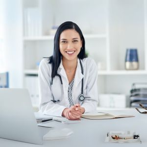 Smiling pediatrician with stethoscope in office, highlighting pediatric board exam prep for initial certification success.