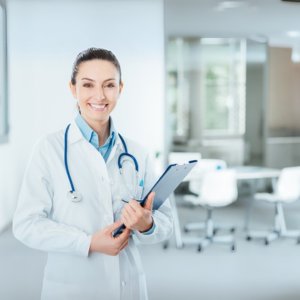 Smiling doctor with stethoscope and clipboard in clinic, representing CME courses for pediatricians to earn credits and stay certified.